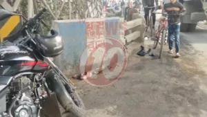 Motorcycle parked beside road with pedestrians and bicycles.