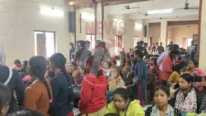 Crowded room with people seated and standing.