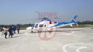 Blue helicopter on helipad with people nearby.